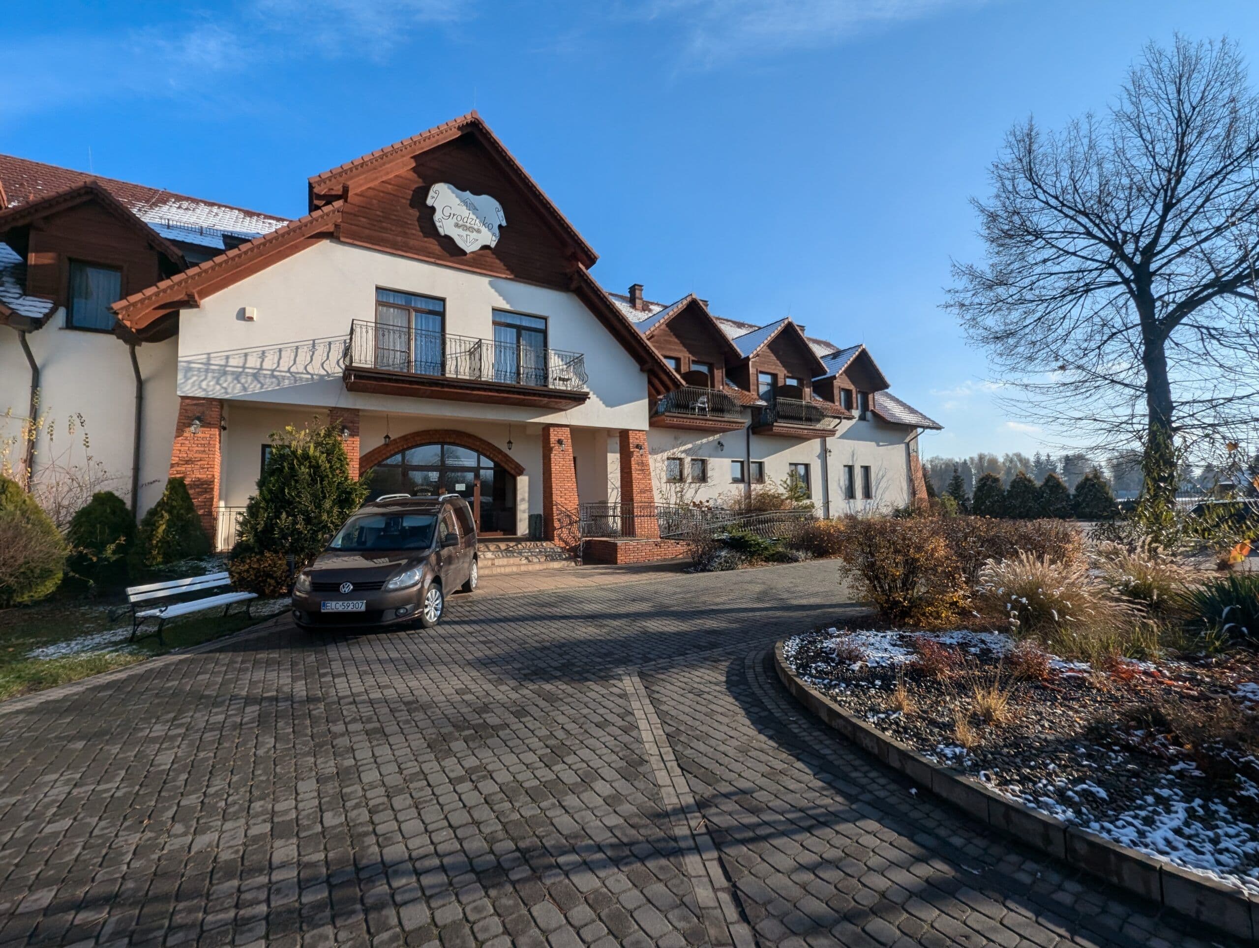 Okna aluminiowe w kolorze drewna oraz aluminiowe drzwi wejściowe z łukowymi doświetlami.