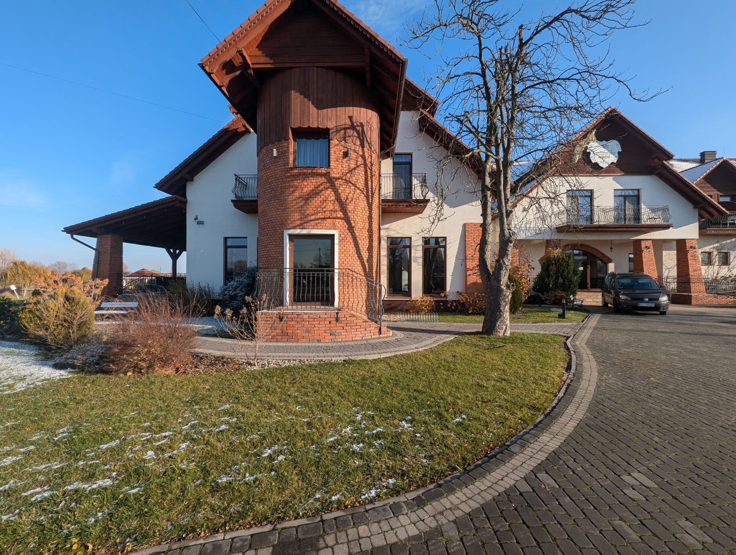 Okna aluminiowe w kolorze drewna oraz aluminiowe drzwi wejściowe z łukowymi doświetlami.